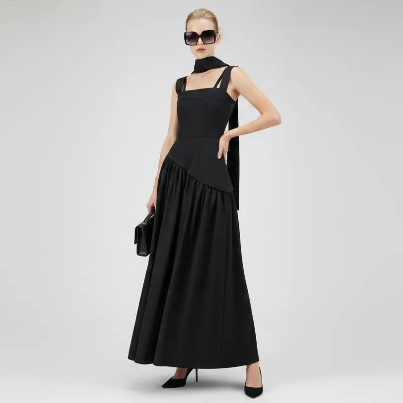 Woman wearing a black sleeveless dress with a high collar on a white background